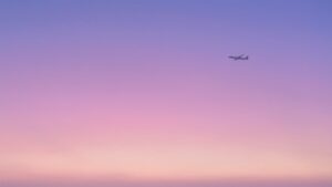 紫ピンク色の空を飛ぶ飛行機