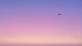 紫ピンク色の空を飛ぶ飛行機